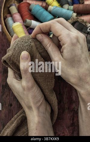 Women's hands in the process stepania holey socks on the background of sewing thread Stock Photo