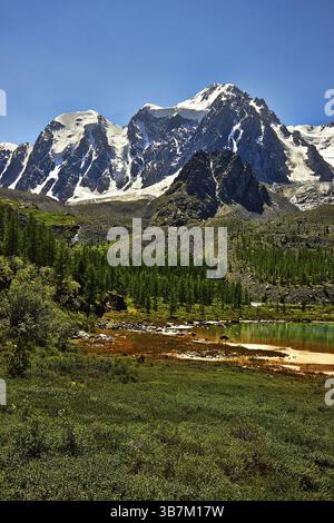 snow-covered Altai mountains reflect in Akkem lake on a cloudy day ...