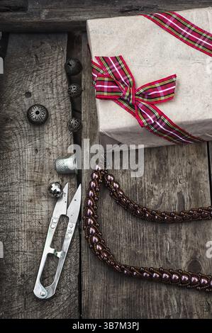 Gift box, craft tools and beads on vintage background Stock Photo