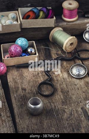 Old scissors, spools of thread, buttons and beads on wooden table Stock Photo