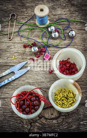 Set of beads in stacks on wooden table with tools for needlework.Selective focus.Photo tinted Stock Photo