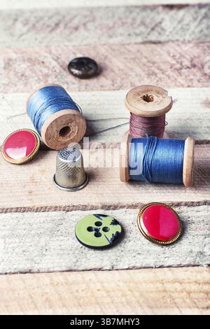 Spools of thread and various buttons on wooden background Stock Photo