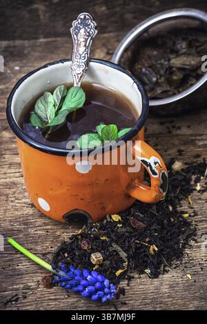 Enamel cup with herbal tea amid scattered on the welding table Stock Photo