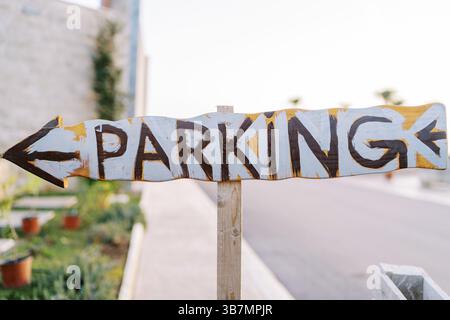 Wooden pointer with an arrow. Caption: Parking. Stock Photo