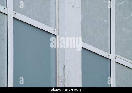 Close-up view of a modern building's facade, highlighting the contrast between white concrete and teal windows Stock Photo