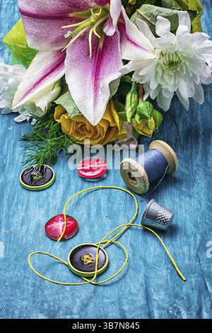 Sewing accessories with a bouquet of fresh flowers on turquoise background Stock Photo
