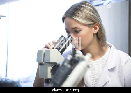 Beauty researcher looking through microscope in laboratory Stock Photo