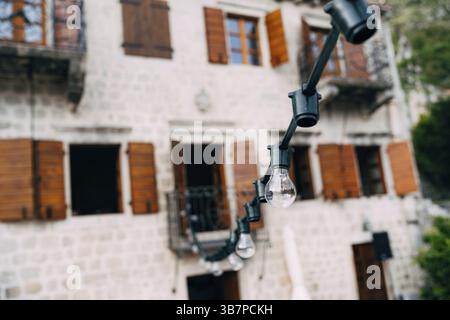 Off the garland of incandescent lamps against the background of the old villa. Stock Photo