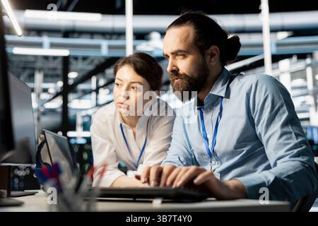 Data center coworkers doing brainstorming, running diagnostic scripts on computer, examining hardware. Server room employees talking, working together to evaluate performance metrics Stock Photo