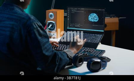 Computer scientist updating artificial intelligence neural networks, writing binary code scripts. Remote worker in apartment office uses digital device programming to upgrade AI, camera A Stock Photo