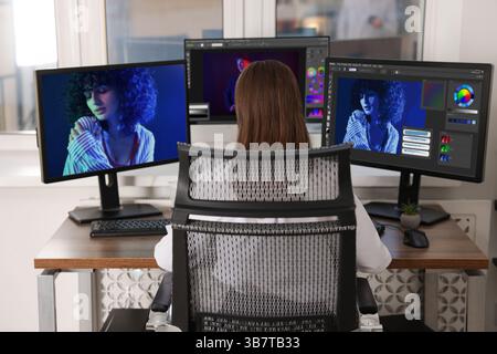 Designer working on different computers at table in office, back view Stock Photo