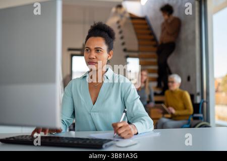 Business woman working on laptop computer reading financial document report in office Stock Photo