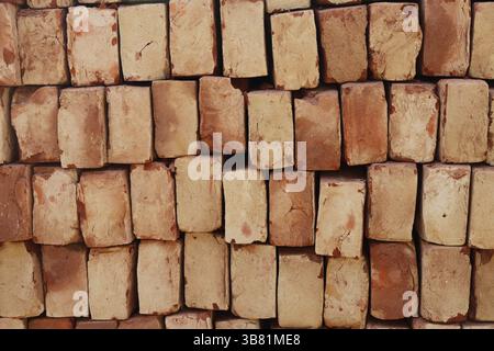Detailed close up showcases a stack of pale red and tan bricks, arranged in a textured pattern, highlighting construction materials and aged surfaces. Stock Photo