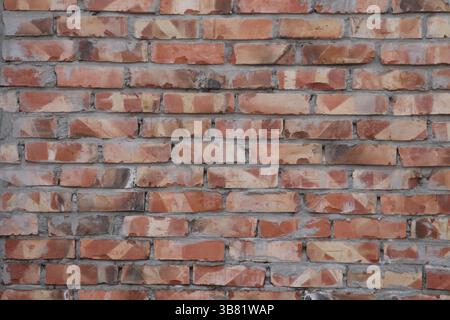 Displaying a red brick wall with irregular surface textures, perfect for backgrounds, architectural details, or creating a vintage industrial aestheti Stock Photo