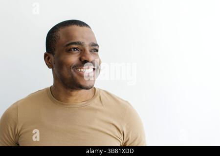 Closeup portrait of smiling black man looking away with hopeful expression. Stock Photo