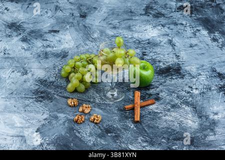 white grapes, green apple with cinnamon, walnuts, glass of whisky high angle view on a dark blue marble background Stock Photo