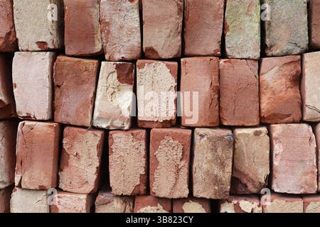 Up-close photograph capturing a neatly organized stack of red bricks, presenting a textured surface and showcasing brick detail, perfect for backgroun Stock Photo