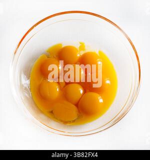 Egg yolks in glass bowl on a white table. Yolks for making dough. Yolks for cooking. Directly above. Stock Photo