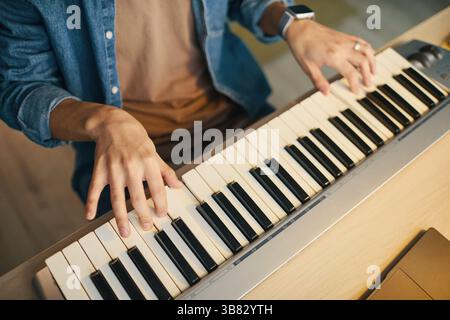 Close-up view of male hands skillfully playing melodies on electric keyboard. Detailed composition shows fingers creating music on black and white key Stock Photo