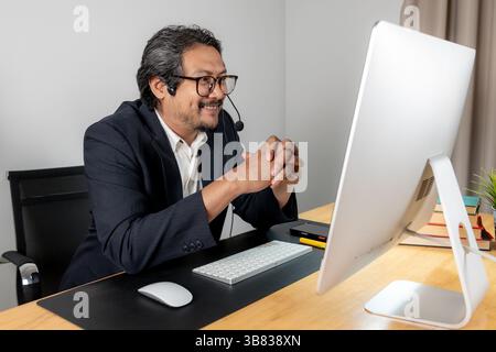 Modern teamwork in action, a male executive wearing a headset, actively discussing project plans with his colleagues in a professional office environm Stock Photo
