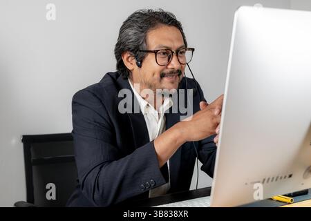 Modern teamwork in action, a male executive wearing a headset, actively discussing project plans with his colleagues in a professional office environm Stock Photo