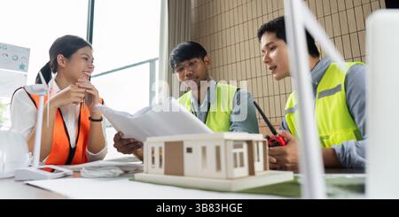 Green Technology and Team Collaboration. Engineers analyzing sustainable building plans together. Stock Photo