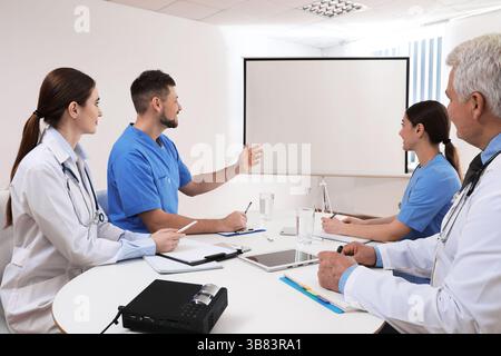 Team of doctors using video projector during conference indoors Stock Photo