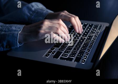 Woman working with modern laptop on dark background, closeup Stock Photo