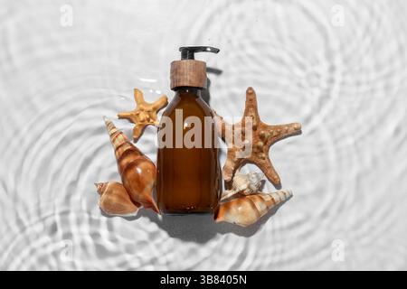 Composition with bottle of shower gel, seashells and starfishes in water on light background Stock Photo