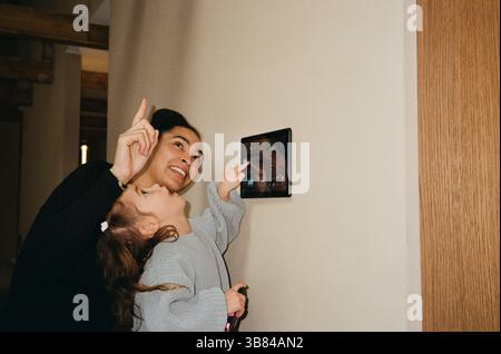 Smiling woman pointing by daughter using digital tablet at home Stock Photo