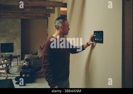 Man adjusting temperature of house through smart home app at home Stock Photo