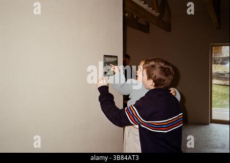 Siblings operating tablet PC mounted on wall at home Stock Photo