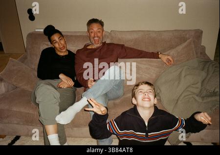 Playful family making faces while sitting on sofa at home Stock Photo