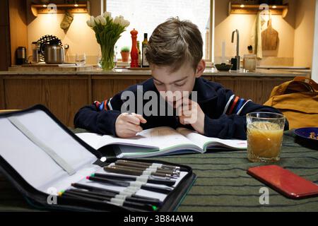 Thoughtful boy with set of colored pencils on table at home Stock Photo