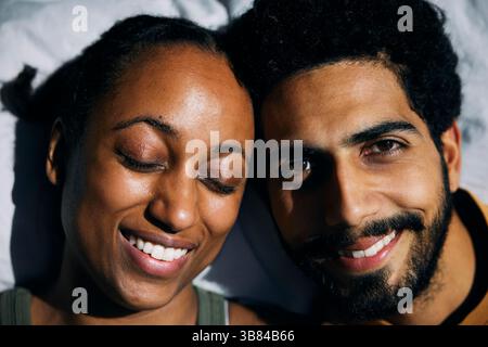 Close-up portrait of smiling man leaning on girlfriend with eyes closed Stock Photo