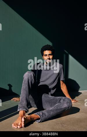 Smiling man sitting on floor near wall at home Stock Photo