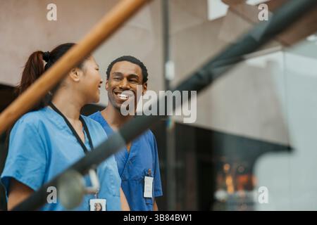 Happy male and female wearing medical scrubs talking with each other Stock Photo