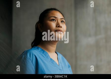 Thoughtful young female healthcare worker looking away Stock Photo