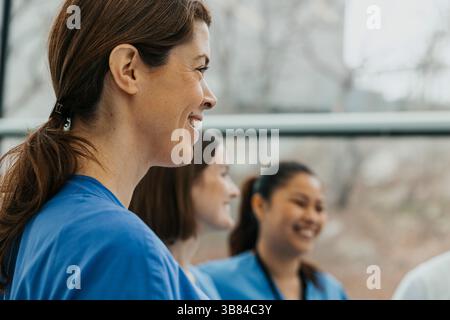 Smiling female healthcare worker in meeting with team at clinic Stock Photo