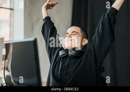 Relaxed non-binary business entrepreneur stretching while sitting at desk in office Stock Photo