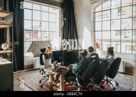 Group of multiracial software engineers working on desktop PC while sitting at desk in tech startup office Stock Photo