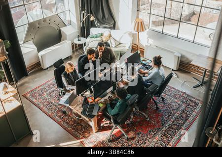 High angle view of focused multiracial IT professionals working on technologies while sitting at desk in tech hub Stock Photo