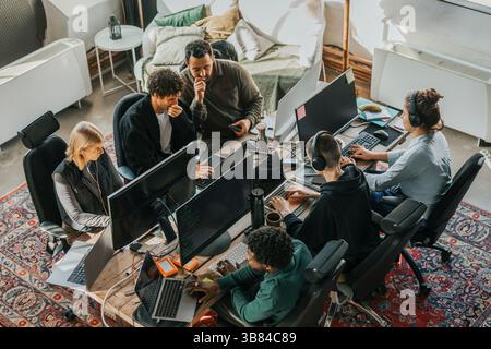 High angle view of multiracial computer programmers coding while sitting at desk in startup office Stock Photo