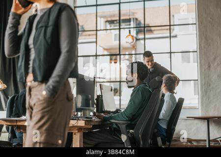 Focused male computer programmer coding on desktop PC while sitting at desk in tech hub Stock Photo