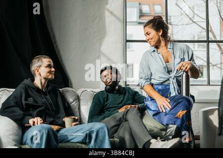 IT professionals talking with each other while sitting on sofa in tech hub Stock Photo