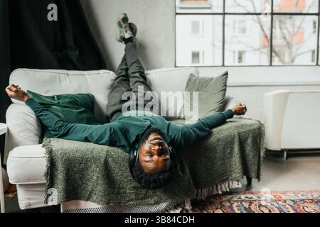 Carefree businessman listening to music while lying on sofa with feet up in office Stock Photo