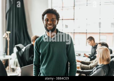 Portrait of smiling curly haired male computer programmer standing in office Stock Photo