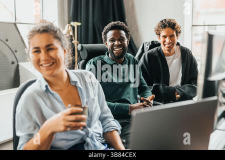 Happy male and female computer programmers sitting on chair while looking away in office Stock Photo