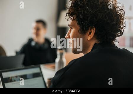 Rear view of curly haired young male computer programmer looking away Stock Photo