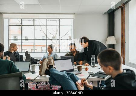 Multiracial IT professionals talking with each other while working at desk in tech hub Stock Photo